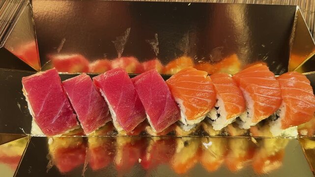 Sushi rolls uramaki with salmon and tuna in golden packaging