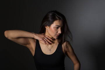 A woman with black hair wakes up in the morning in a white blanket and catches the rays of the sun. The portrait is creative, with brown eyes. High quality photo