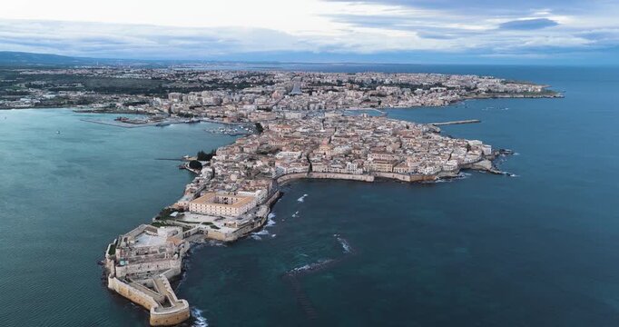 Aerial view of the ancient island city, with its sandstone buildings contrasting against the deep blue sea, Ortigia Island, Syracuse, Italy.