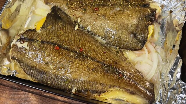 Two baked flounders in the metal baking tray, top view