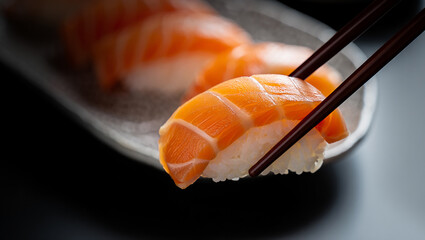 Sushi piece held by chopsticks over a plate