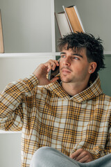 young man with mobile phone at home in casual outfit