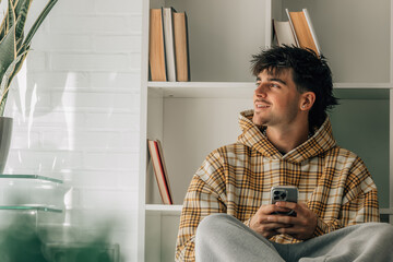 teenager at home with cell phone sitting on the floor