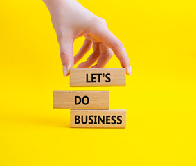 Lets do business symbol. Concept word Lets do business on wooden blocks. Businessman hand. Beautiful yellow background. Business and Lets do business concept. Copy space