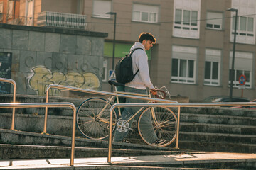 young man or student on the street with vintage bicycle at sunset