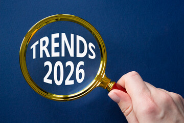 Trends 2026 symbol. Magnifying Glass with words Trends 2026. Businessman hand. Beautiful deep blue background. Business and Trends 2026 concept. Copy space.