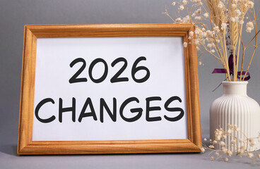 2026 Changes symbol. Concept words 2026 Changes on beautiful wooden picture frame. Beautiful grey background with flower vase. Business and 2026 Changes concept. Copy space.