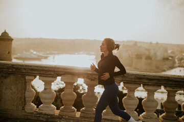 Woman jogging along a waterfront in Malta during the early morning light