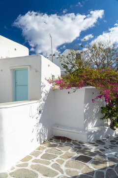 View of whitewashed walls meet the vibrant fuchsia bougainvillea under a bright blue sky, creating a stunning contrast in Old town, Mykonos, Greece.