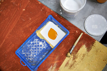 Close-up of a person wearing black gloves painting a wooden surface indoors. DIY home renovation process with brush and paint tray, workshop atmosphere, creative manual work and interior improvement c