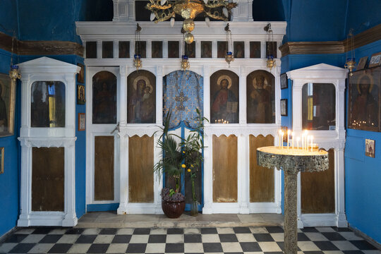 View of a quaint room with religious icons, flickering candles, and striking blue walls, evoking a sense of serenity and reverence, Old town, Mykonos, Greece.