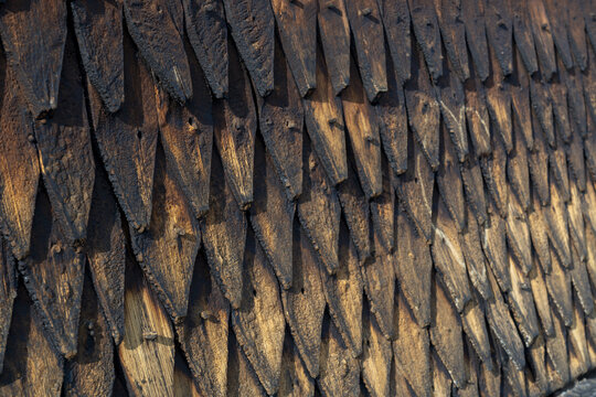 View of weathered, overlapping wooden shingles create a textured tapestry of dark browns and blacks, hinting at aged architecture of stave church, Eidsborg, Telemark, Norway.