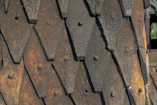 View of weathered, overlapping wooden shingles create a textured tapestry of dark browns and blacks, hinting at aged architecture of stave church, Eidsborg, Telemark, Norway.