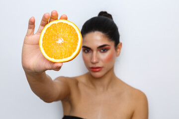 Woman holding orange slice for skincare and beauty
