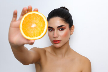 Woman presenting orange slice for vitamin c skincare