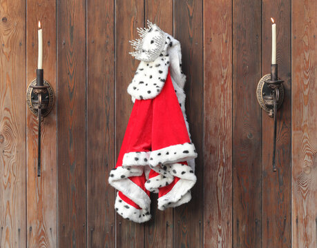 royal robe and crown on a wooden wall with candlesticks