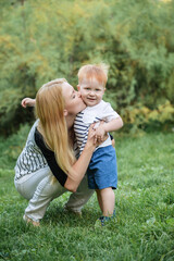 Happy little boy is standing on the grass. Baby is playing with mother in the park in the summer. Protection kids from insects