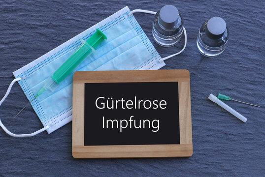 Spritze, Mundschutz,Impfserum und eine Tafel mit der Aufschrift G&uuml;rtelroseimpfung.