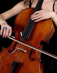 A close-up shot shows a person playing a cello, with their hands on the strings and bow.