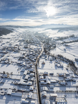Drone aerial of Kacwin in winter, southern Poland. Frosty village, white fields and quiet countryside forming a serene winter scene.