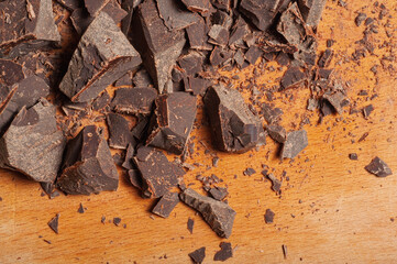 Rich dark chocolate chunks scattered on a wooden surface, creating a delicious texture