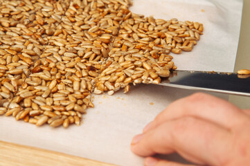 Cutting a star-shaped sunflower seed brittle with a knife on parchment paper