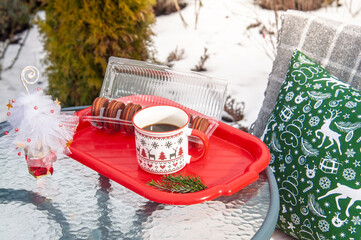 Cozy Christmas coffee break with macarons and festive decorations in the snow
