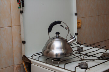 Shiny metal kettle heating up on a vintage gas stove in a kitchen