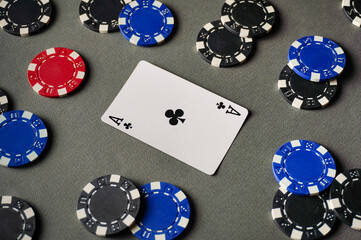 A table is set with various poker chips and an Ace of Clubs card placed in the center. Friends are gathered around the table for game night in an apartment