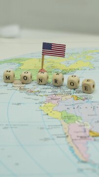 United States foreign policy concept of the Monroe Doctrine represented on a map of the American continents with wooden cubes and a flag, symbolizing opposition to European colonialism