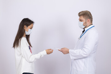 Male doctor in medical mask giving blank white card to woman patient in studio