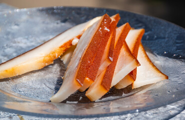 Closeup of fatback lard slices on a glass plate, showing food texture with shallow depth of field. Also known as pork backfat.