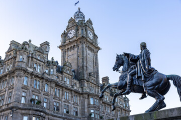 Obraz premium Equestrian statue in front of a stone building with a clock tower in Edinburgh, Scotland.