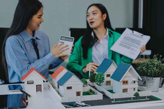 Professional real estate agents brainstorming house project while planning home investment with architectural model and documents - Powered by Adobe
