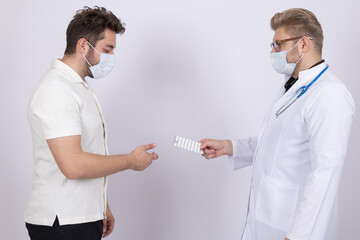 Male doctor in medical mask giving money cash to colleague in hospital room