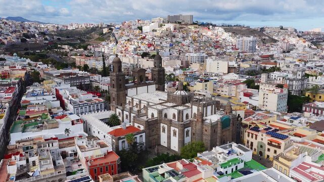 Aerial 4K pans and descents show Catedral de Santa Ana in Vegueta, Las Palmas, twin towers, white and stone facade, narrow streets, plazas, solar panels, Mount Teide.