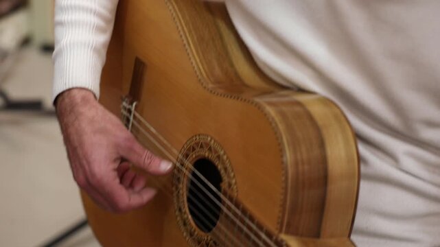 Close-up of musician tuning acoustic guitar using a mobile app on a smartphone screen, ensuring perfect pitch before playing a song during a music lesson.

