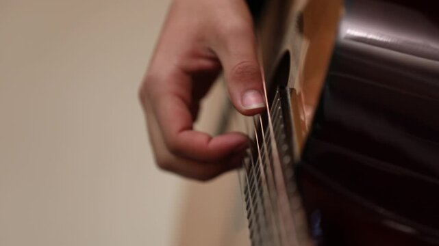 Close-up of musician tuning acoustic guitar using a mobile app on a smartphone screen, ensuring perfect pitch before playing a song during a music lesson.

