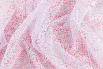 Background image of chaotic waves of openwork white fabric with floral ornaments. Abstract background of white guipure. delicate texture of folds.