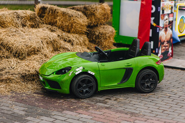 A photo of a green, broken, and cracked plastic children's toy car parked at a rental park after an accident.