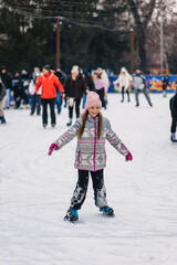 Beautiful happy smiling teenage girl, child skating on ice rink in winter outdoors.