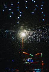 Photograph, background of hanging blue glowing lamps, garlands in the park against the background of snow at night in winter on the street in the city.