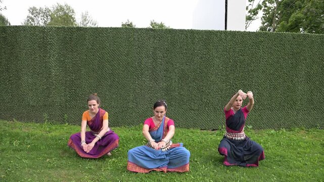 Three female dancers in national costumes dancing in the park on a summer day