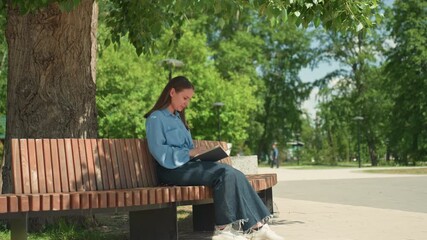 lady preparing tasks amidst nature sunlight, female individual setting goals with notebook in natural surroundings, woman methodically planning her agenda outdoors during bright sunny day