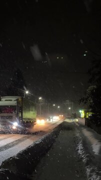 Evening street in winter. It is snowing at night, traffic is full of cars. A captivating shot of heavy, dense snowflakes falling rapidly at night. night traffic in the city