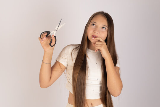 Young Girl Looking at Scissors and Thinking About a New Hair Style