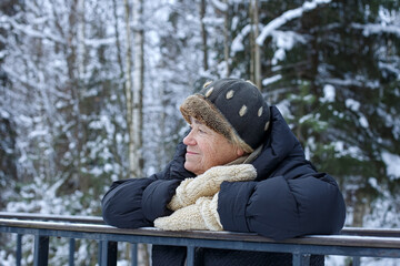 A smiling elderly woman in a winter public park. Winter outdoor recreation for the elderly.