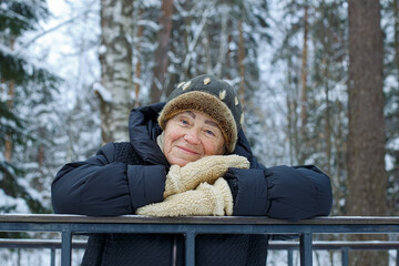 A happy old woman in a winter public park. Winter leisure for elderly people in the fresh air.