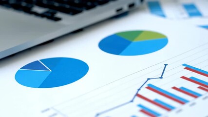 Close up of business charts and laptop displaying financial data analysis with pie and bar graphs. - Powered by Adobe