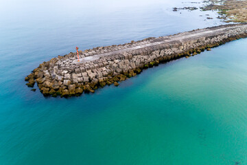 Aerial view of a concrete breakwater extending into the sea.